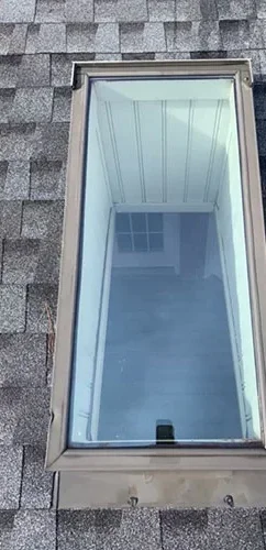 Spotless skylight glass on an asphalt shingle roof after window cleaning.